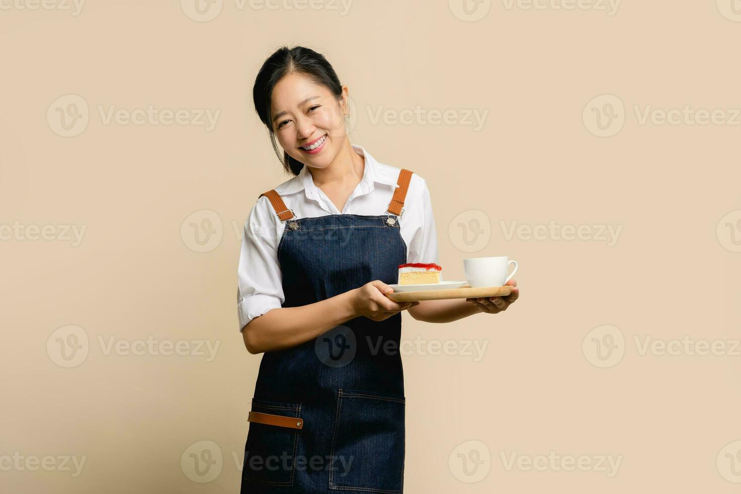 Portrait of asian girl waitress barista wearing apron on light brown background photo