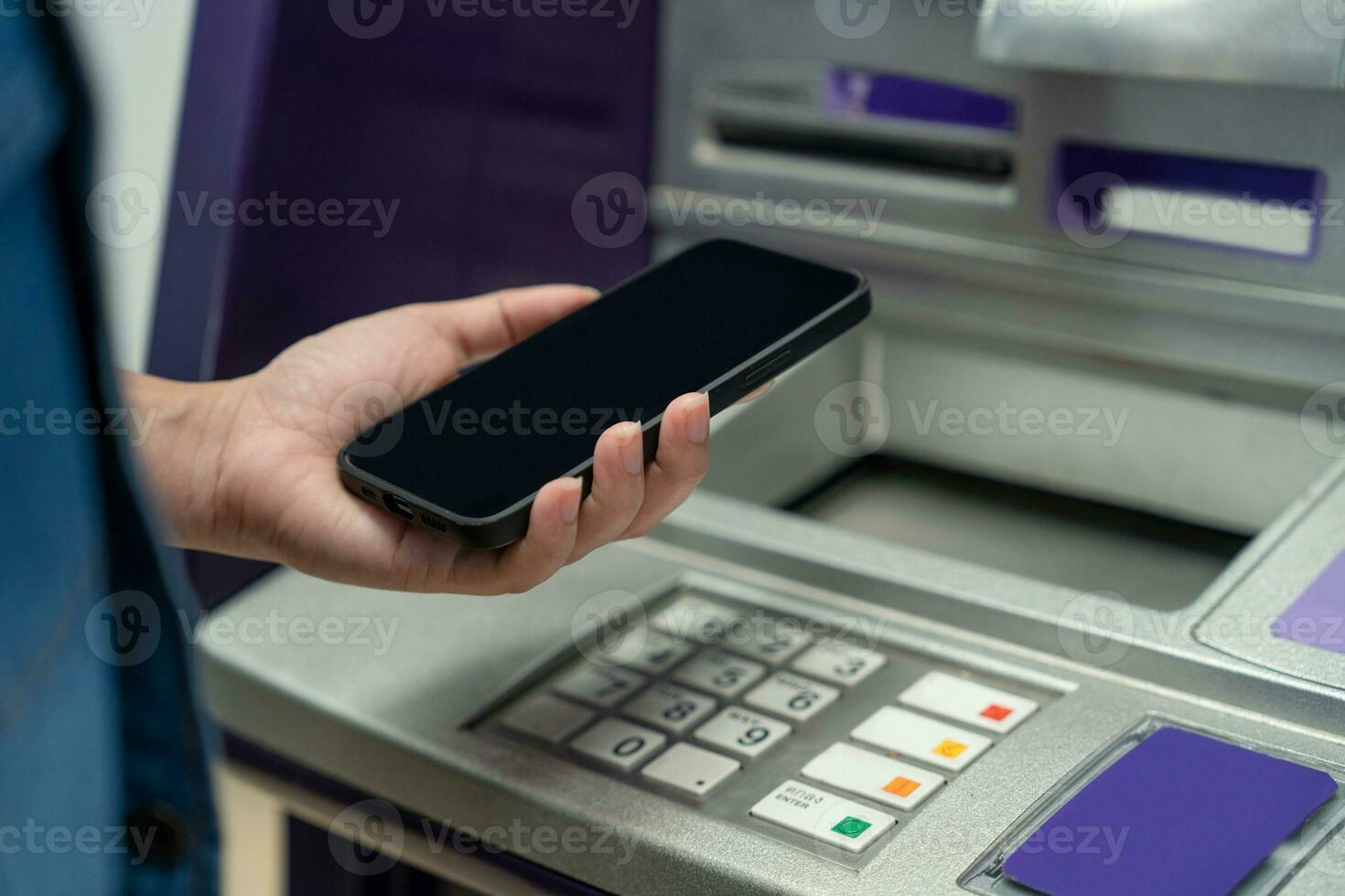 Woman holding a Smartphone financial transactions online on the background, ATM cabinet. Online NFC Banking Concept photo