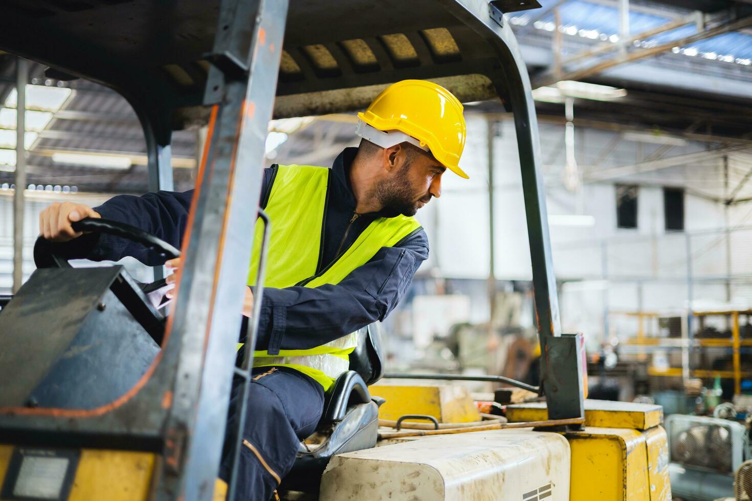 worker wearing helmet with driving forklift backwards in warehouse photo