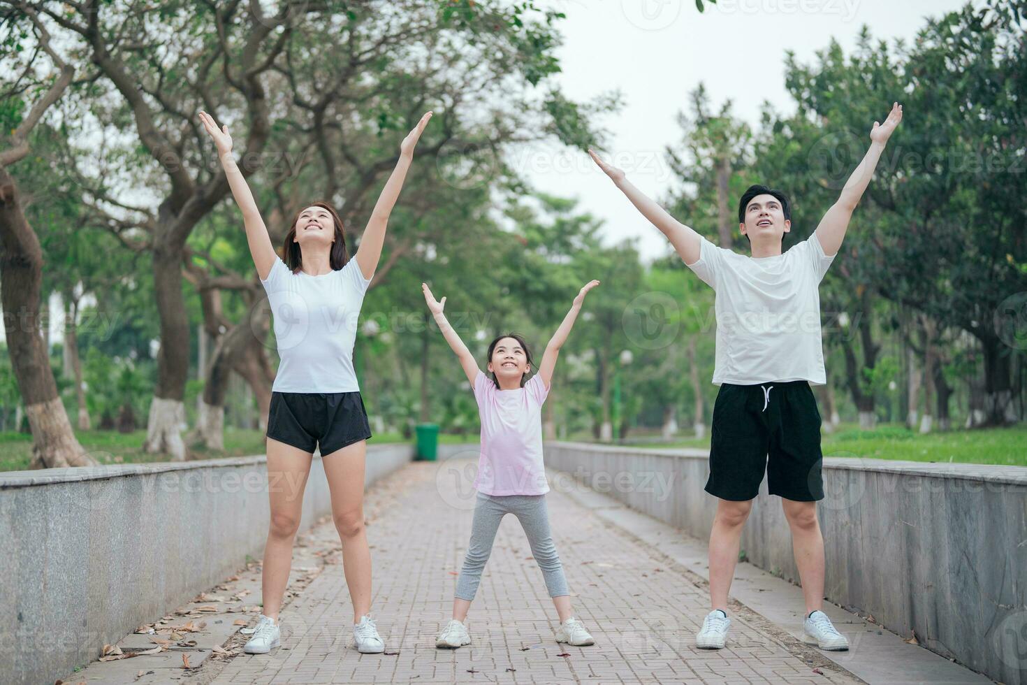 photo of young Asian family exercise at park