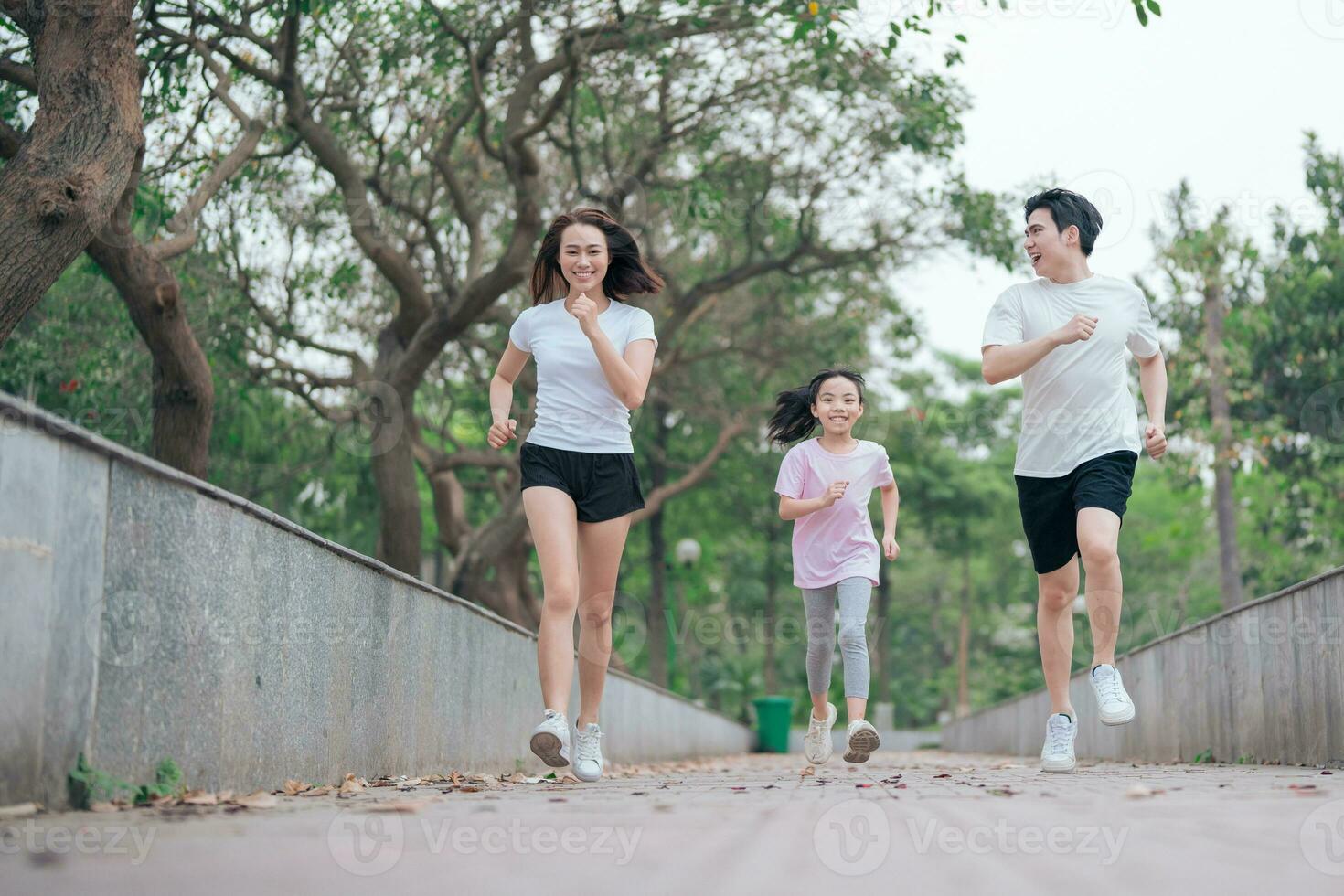 photo of young Asian family exercise at park