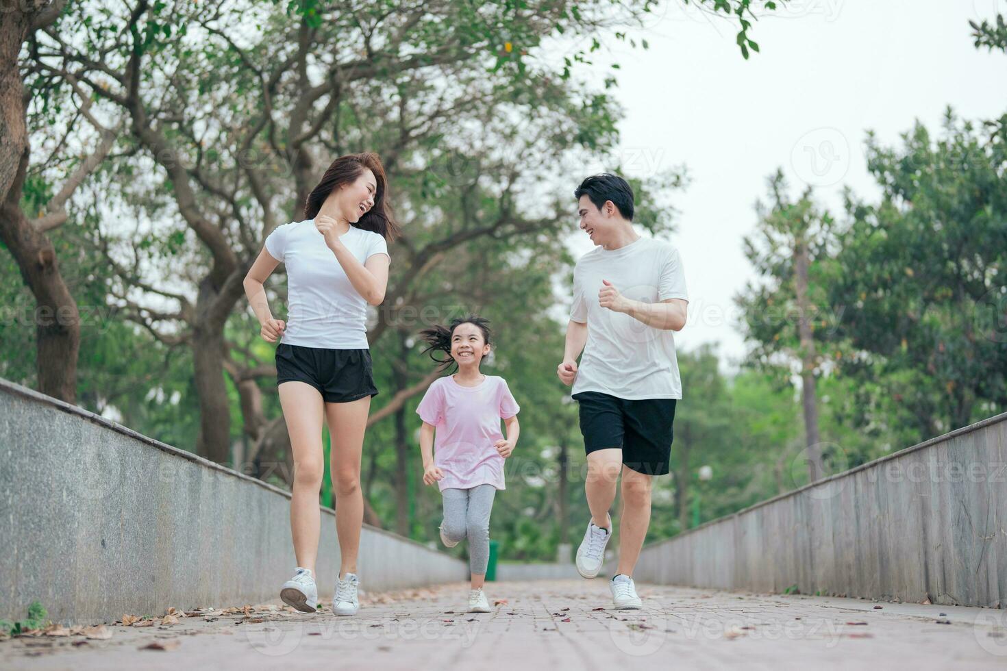 photo of young Asian family exercise at park