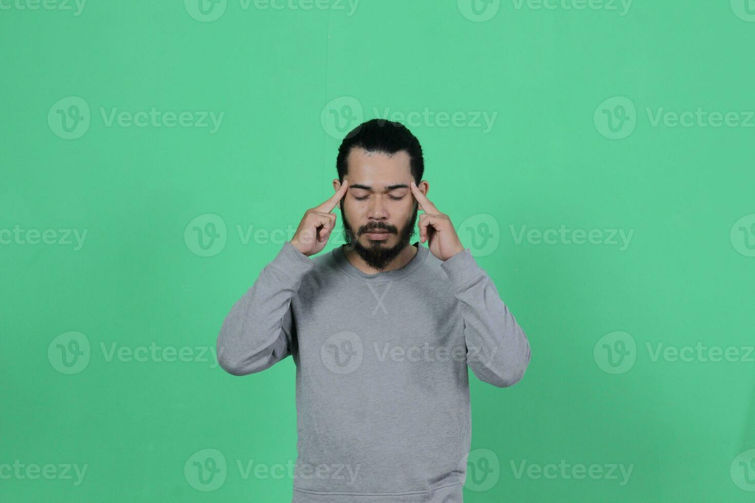 bearded asian man poses wearing a gray shirt against a green background photo
