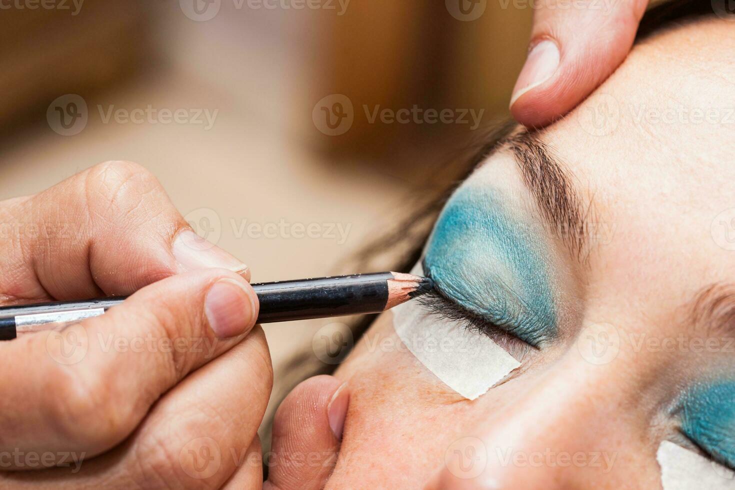 Make up artist using masking tape to create cat eyes photo