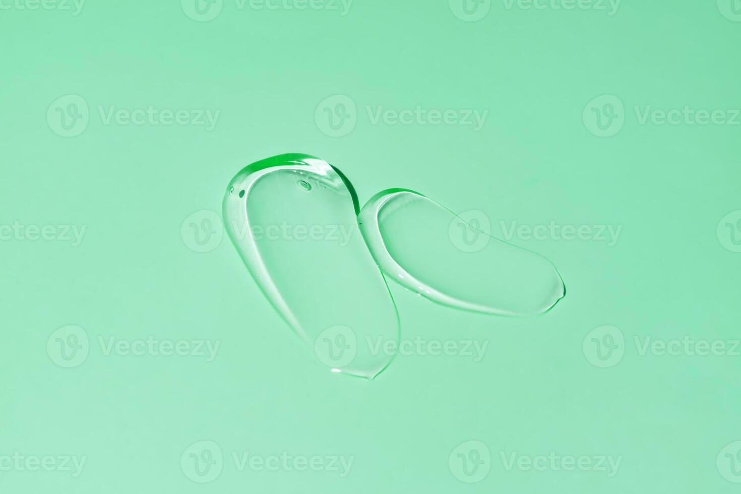 Liquid gel smear isolated on green background. Beauty cosmetic smudge such as pure transparent aloe lotion, facial jelly serum, cleanser, shower gel or shampoo top view. photo