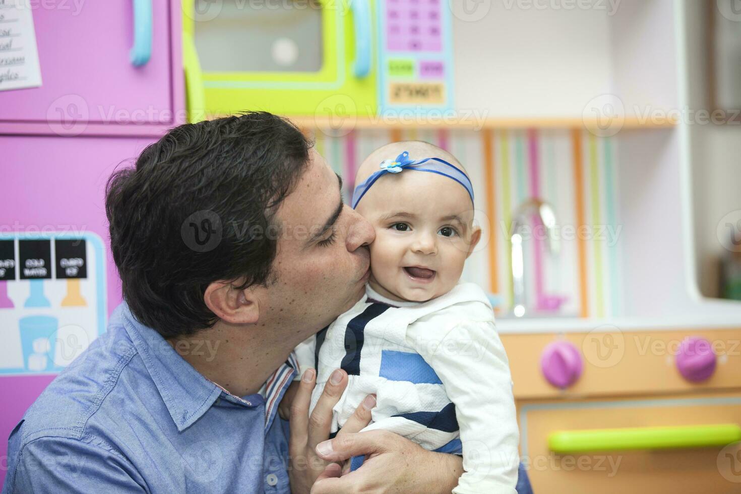 Young father playing with his six months old baby girl indoors. photo