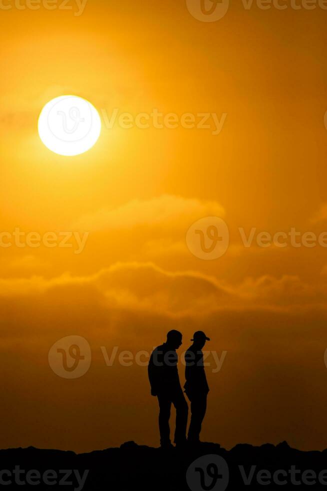 Silhouette of two men at a beautiful orange sunset. Tranquility concept photo