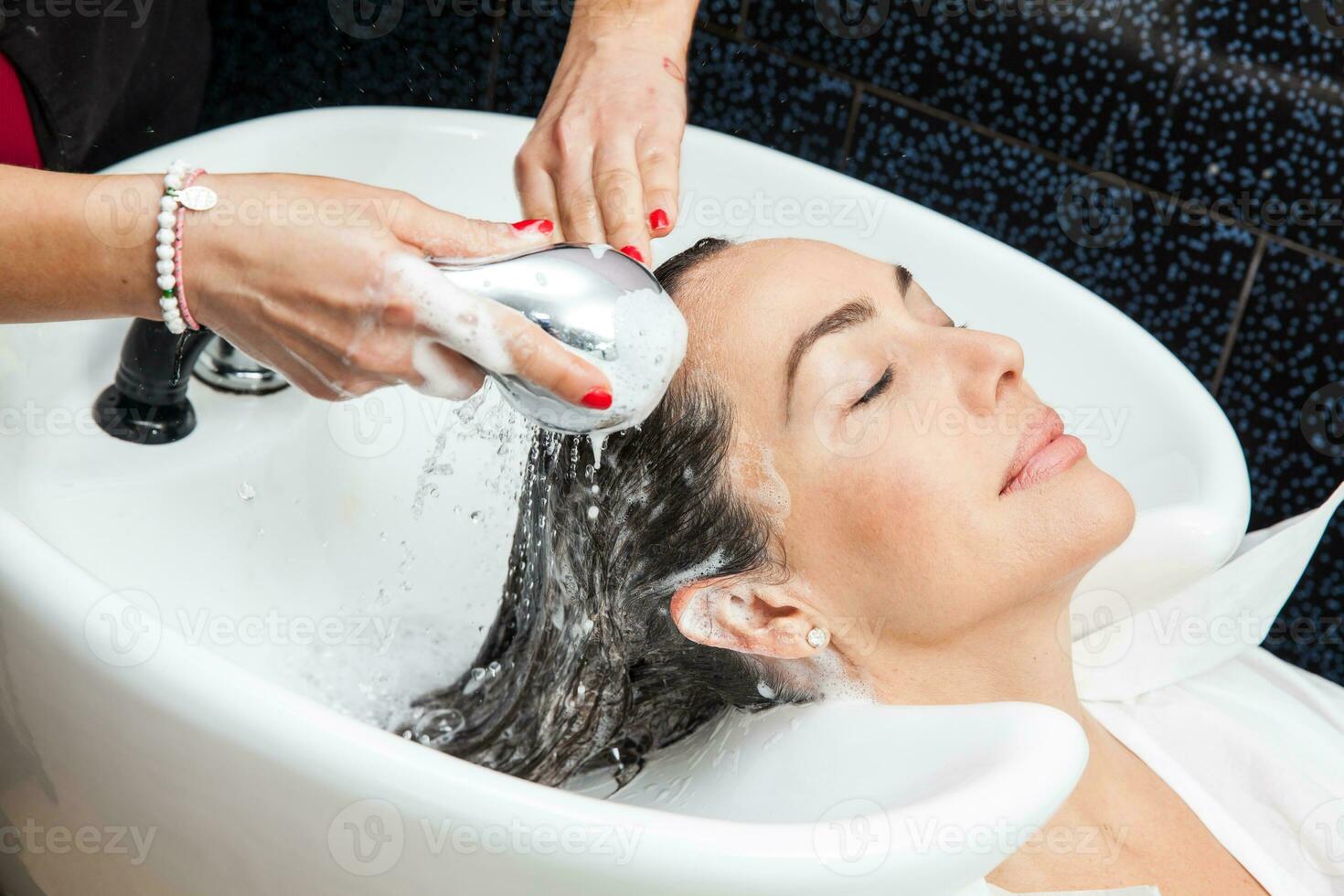 White woman getting a hair wash procedure in a beauty salon photo