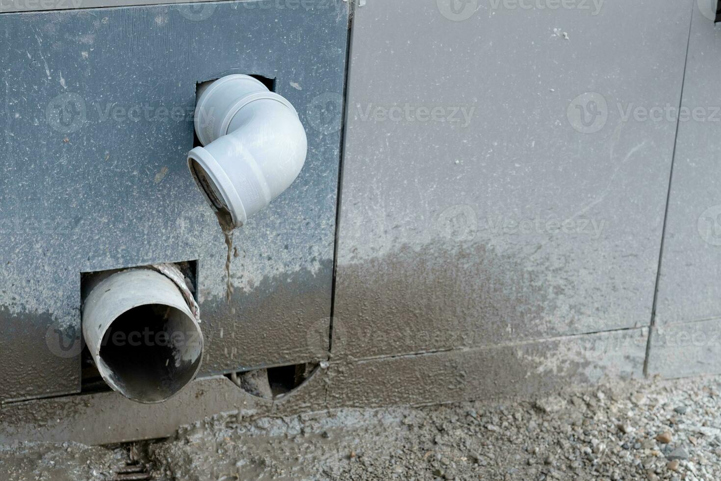 protruding plastic pipes from the wall from which dirt flows into the street. Sewer or drain pipe from the street side photo