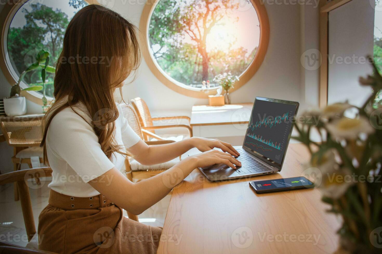 Woman using laptop - smartphone planning, strategy, Stock market. Businesswoman working in the cafe. Technical price graph - indicator, red and green candlestick chart, stock trading computer screen. photo