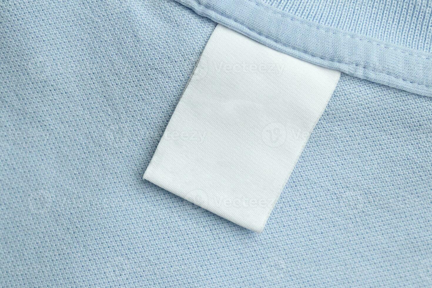 White blank laundry care clothes label on blue shirt fabric background photo