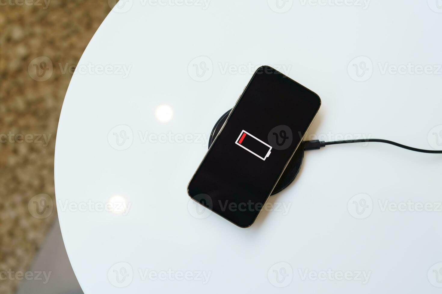 Charging mobile phone battery with wireless charging device in the table. Smartphone charging on a charging pad. Mobile phone near wireless charger Modern lifestyle technology concept. photo