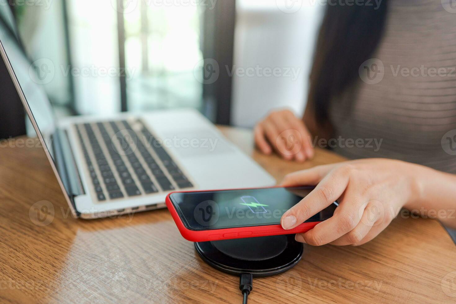 Charging mobile phone battery with wireless charging device in the table. Smartphone charging on a charging pad. Mobile phone near wireless charger Modern lifestyle concept. photo