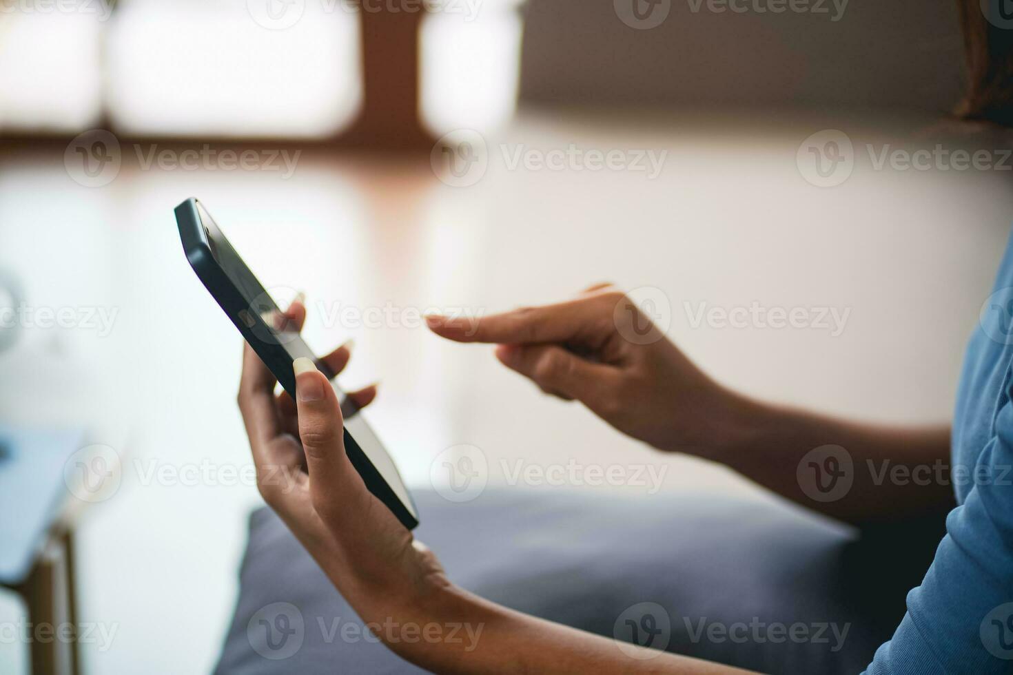 Asian Woman controlling smart home. mobile phone with smart home app in living room. touch screen ai technology. Remote home control system photo