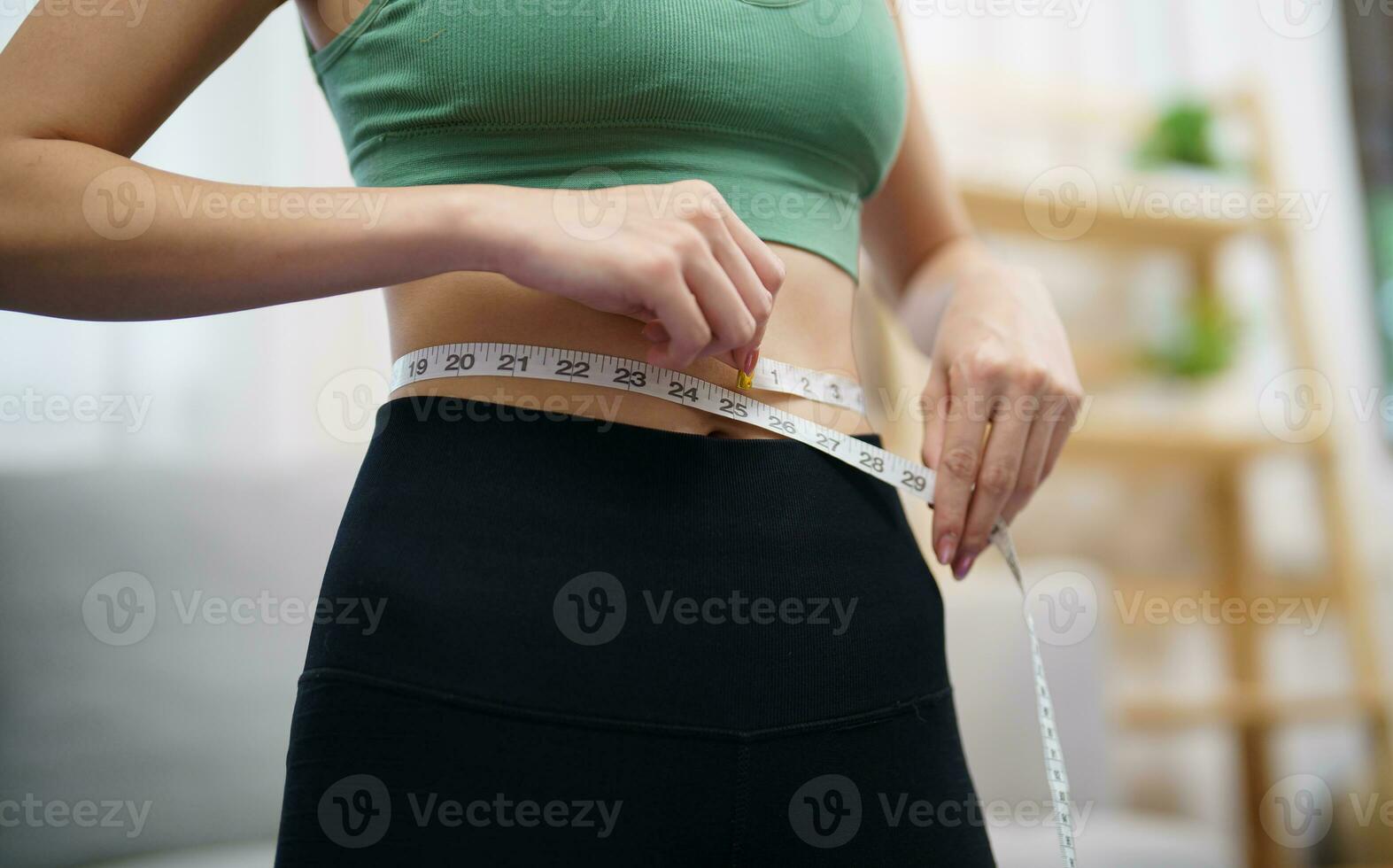 Asian healthy woman dieting Weight loss. Slim woman measuring waist with measure tape after diet at home weight control. photo
