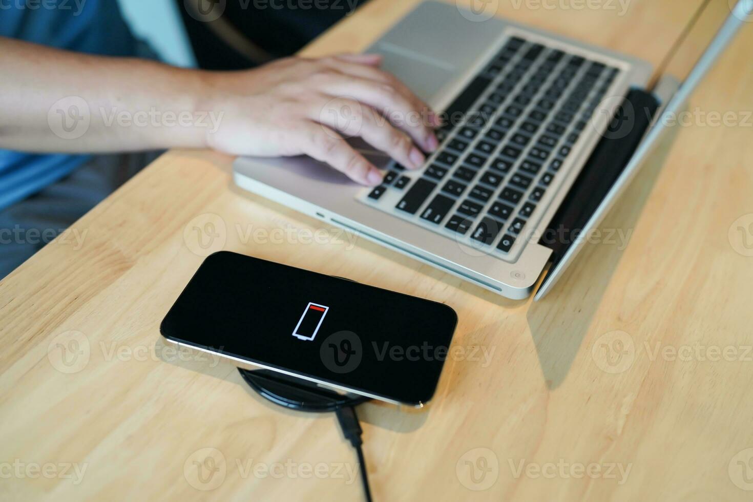 Charging mobile phone battery with wireless charging device in the table. Smartphone charging on a charging pad. Mobile phone near wireless charger Modern lifestyle technology concept photo