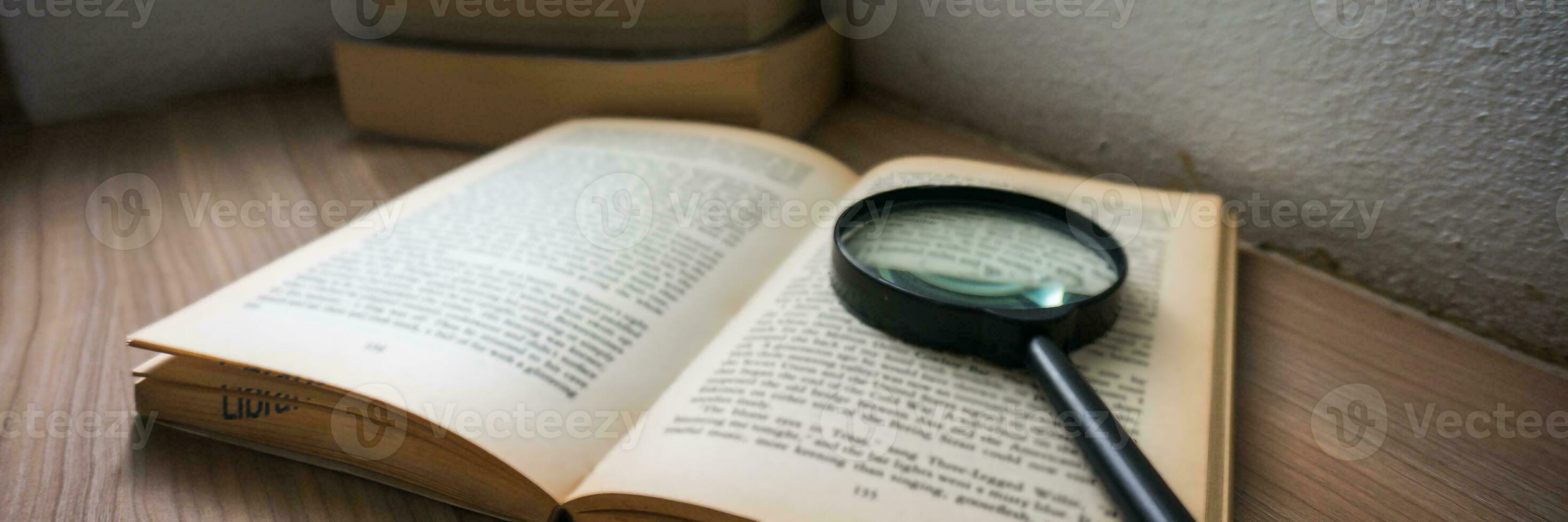 Books and a magnifier Research concept. Magnification glass over a opened book. photo