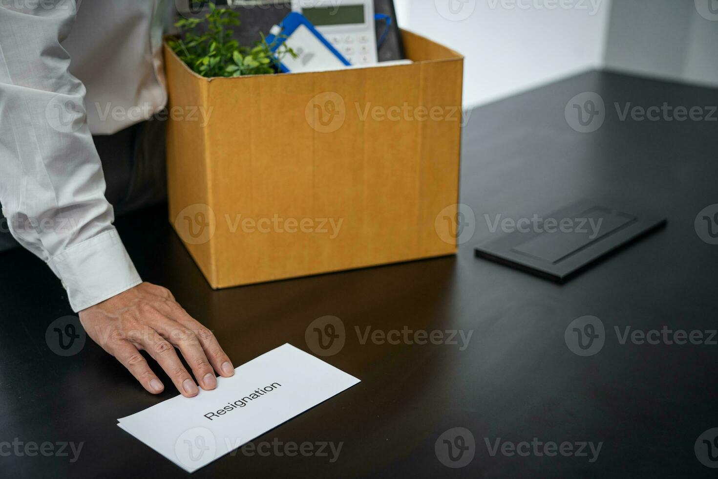 Business man sending resignation letter and packing Stuff Resign Depress or carrying business cardboard box by desk in office. Change of job or fired from company photo