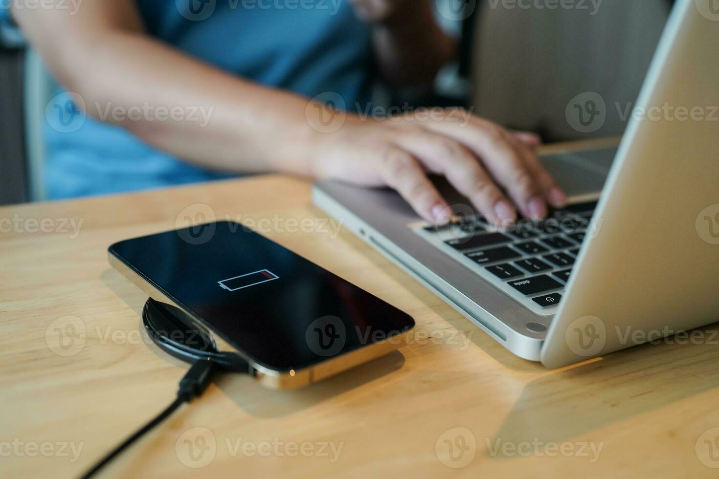 Charging mobile phone battery with wireless charging device in the table. Smartphone charging on a charging pad. Mobile phone near wireless charger Modern lifestyle technology concept photo
