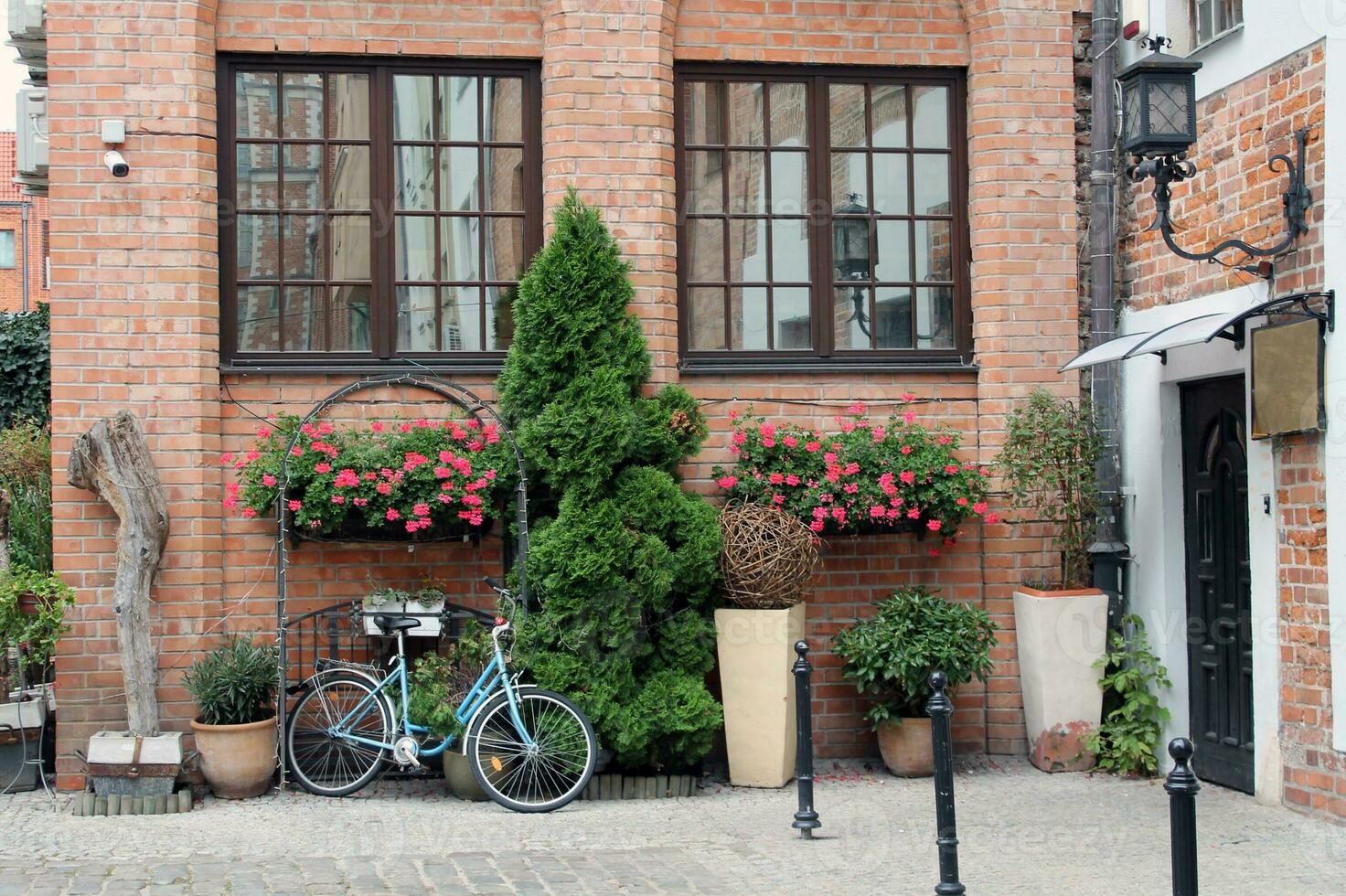 The backyard of an old red brick house in the Polish city of Gdansk with two large windows, a back door, flower beds photo