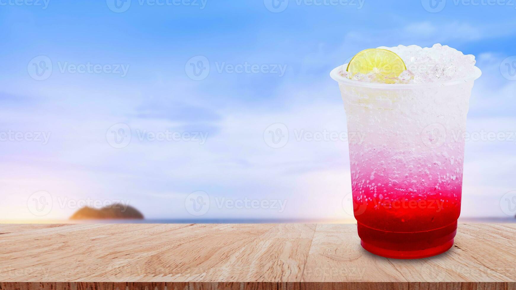Italian soda made from fruit syrup drink mix in plastic cup on wooden table. Lemon, Red cocktail summer refreshment drink, Summer drinks with ice photo