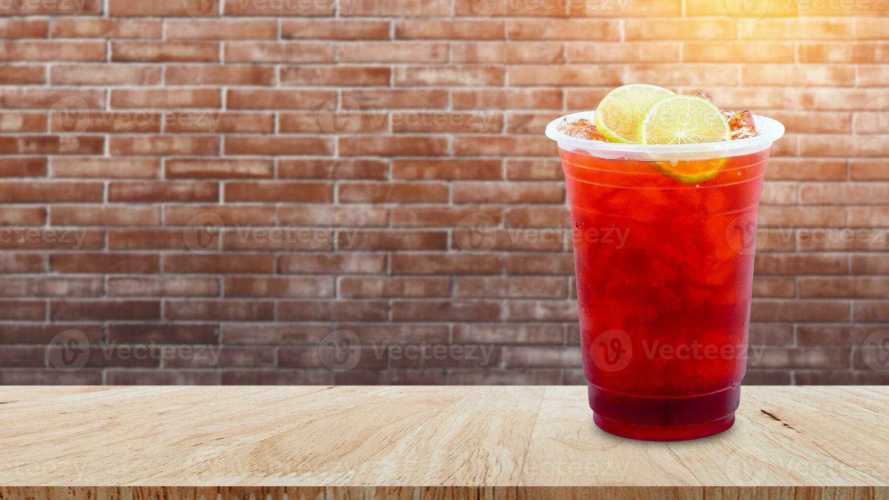 Iced tea and lemon slices on wooden table on brick wall background, Summer drinks with ice photo