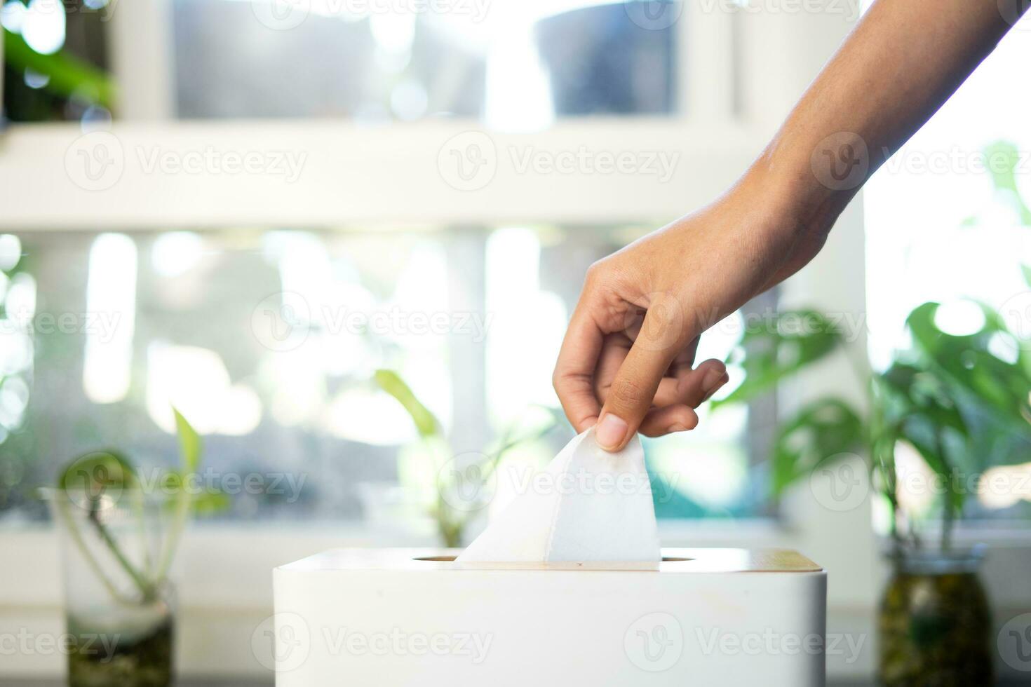 hand pulling tissue from box in living room photo