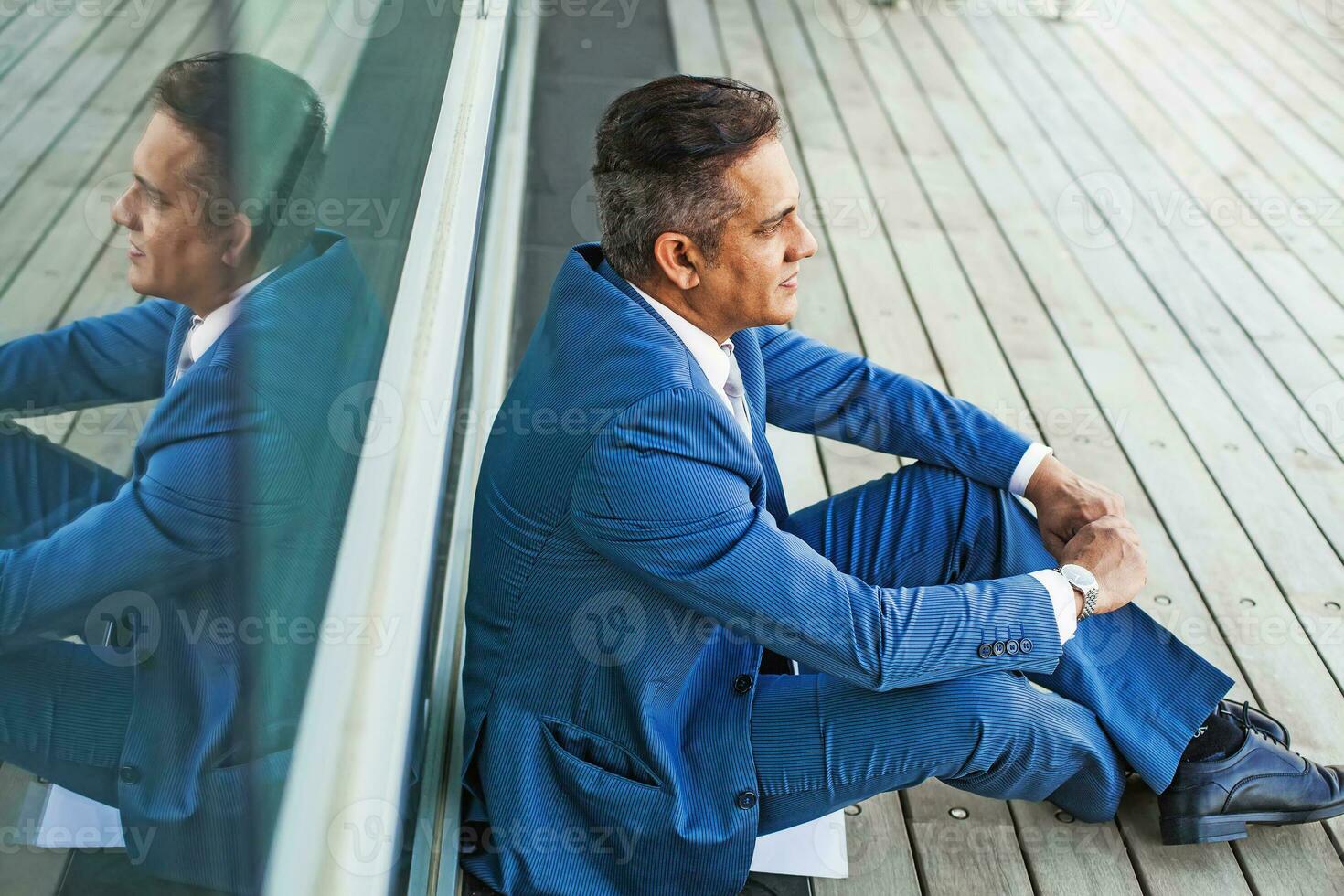 mixed-race man sitting wearing a blue suit photo