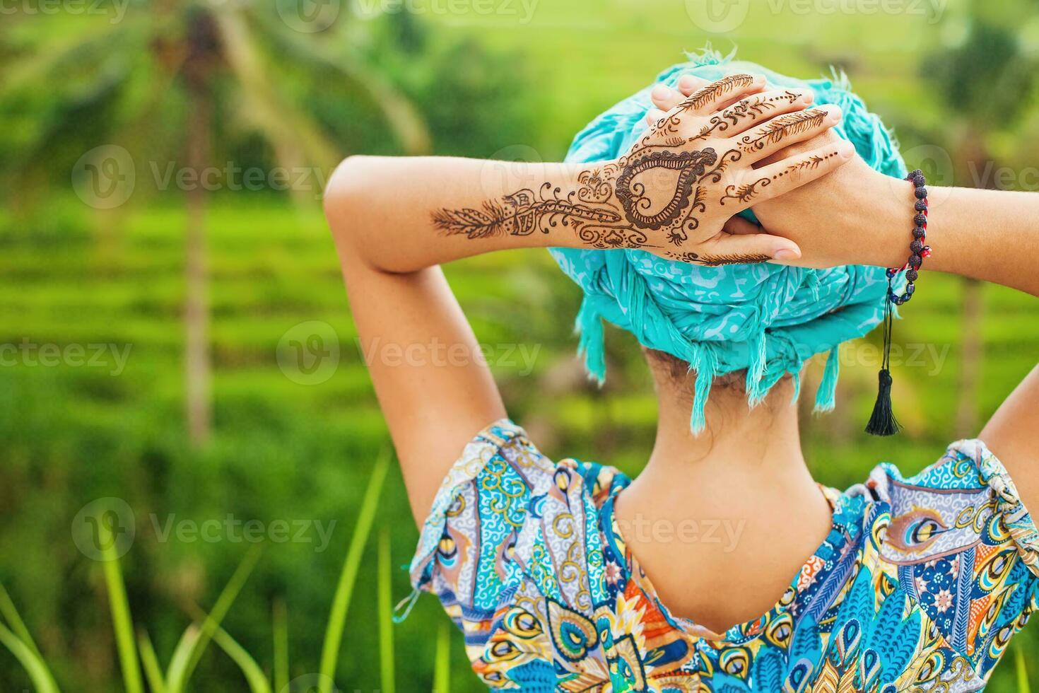 rare view of a woman looking at a rice field with mehendi tattoo on her hand photo