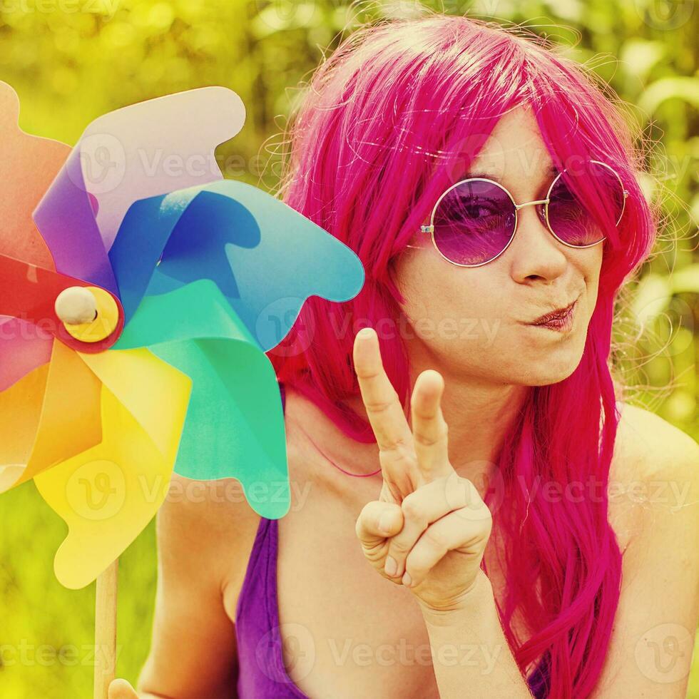 optimistic young woman wearing pink wig posing outdoors photo