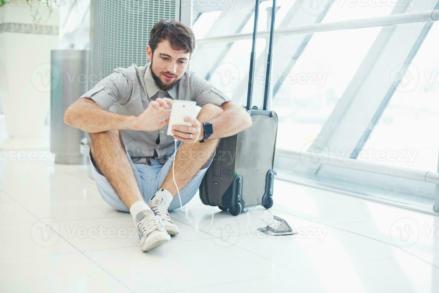 man waiting for his flight in the international airport and calling on phone photo