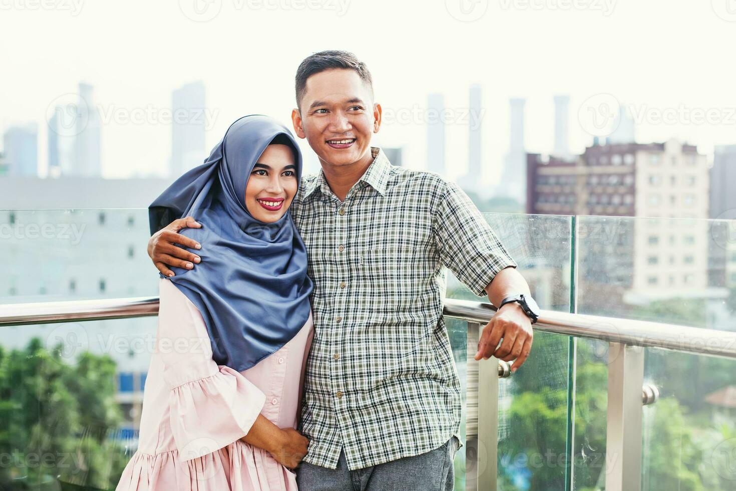 Happy Indonesian couple hugging on a balcony over Jakarta city view photo