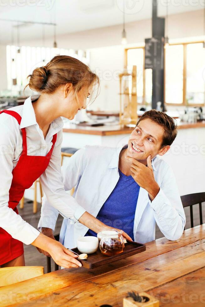 waitress serving tea for a client in restaurant photo