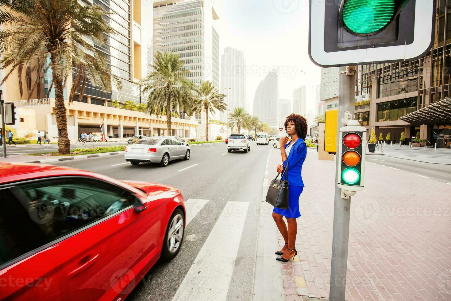 hermosa africano mujer esperando a cruzar el la carretera en un calle de dubai foto