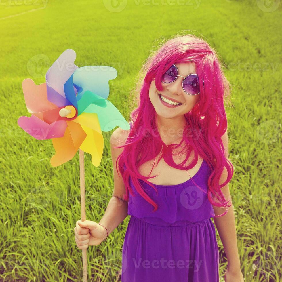 optimistic young woman wearing pink wig posing outdoors photo