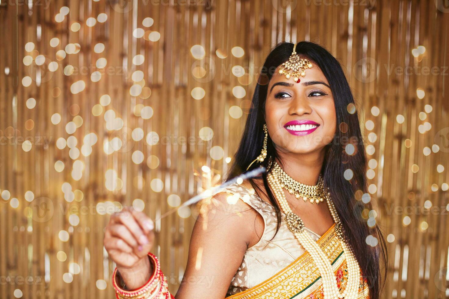 Beautiful Indian woman in traditional clothes holding a sparkler in the evening to celebrate Diwali festival photo