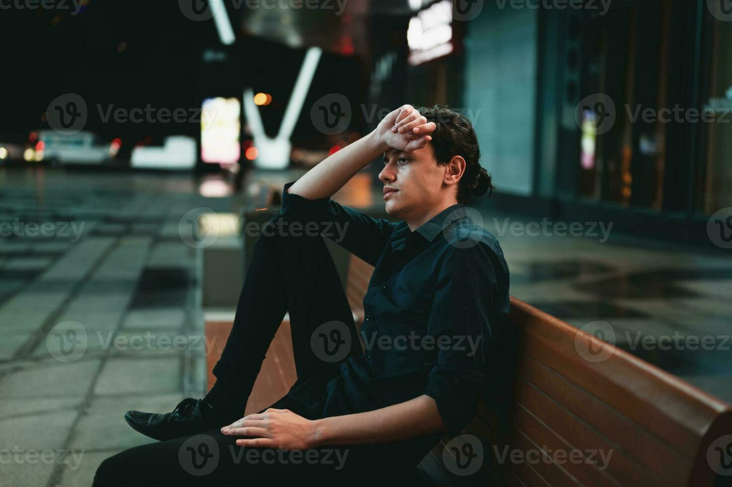 Sad depressed man sitting on a bench alone at night photo