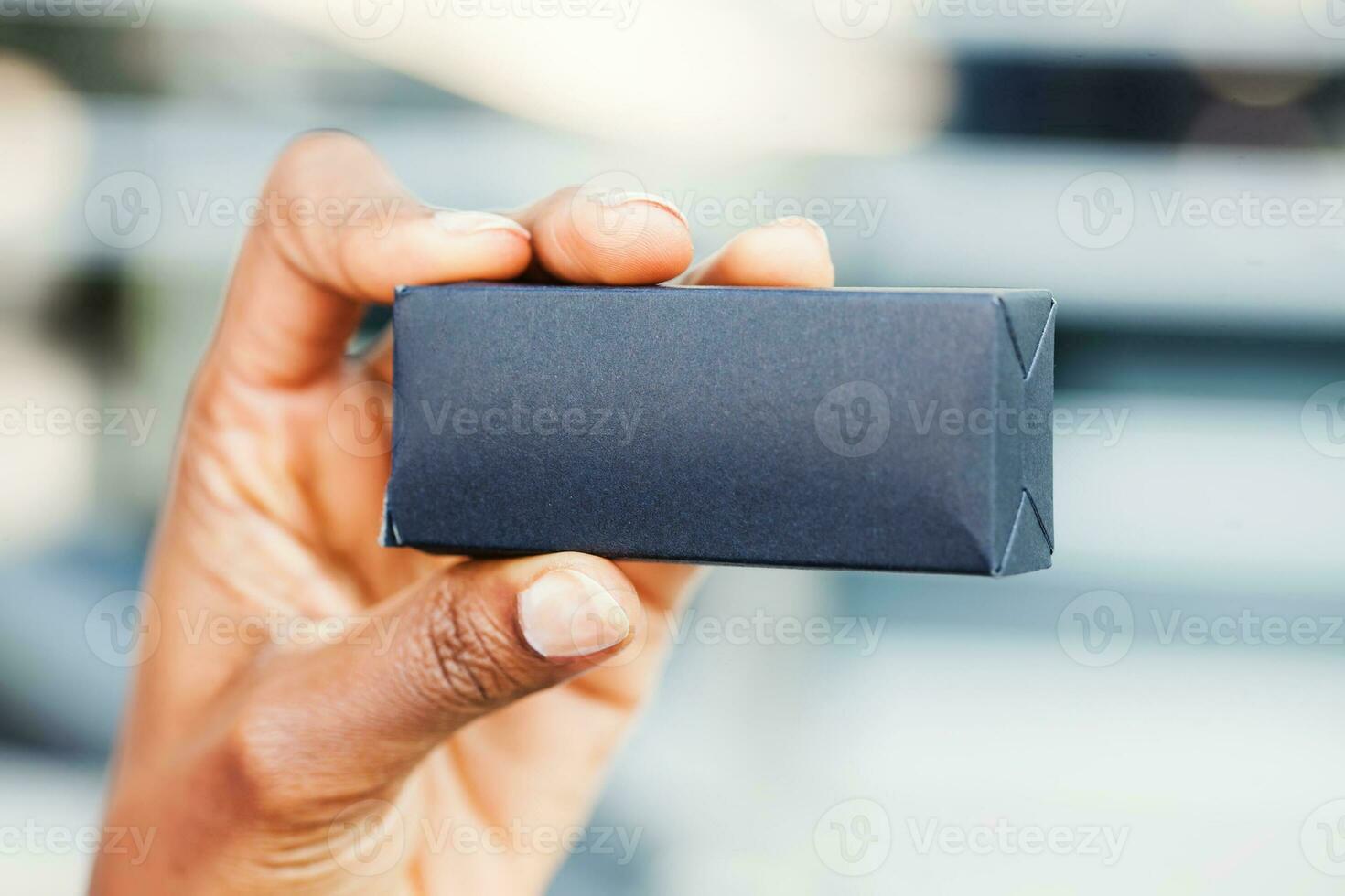 a small black paper box held by an African woman photo