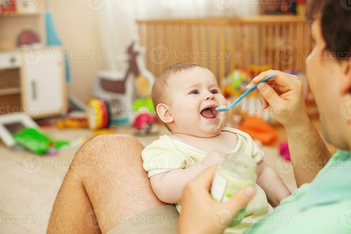 father feeding his cheerful baby photo