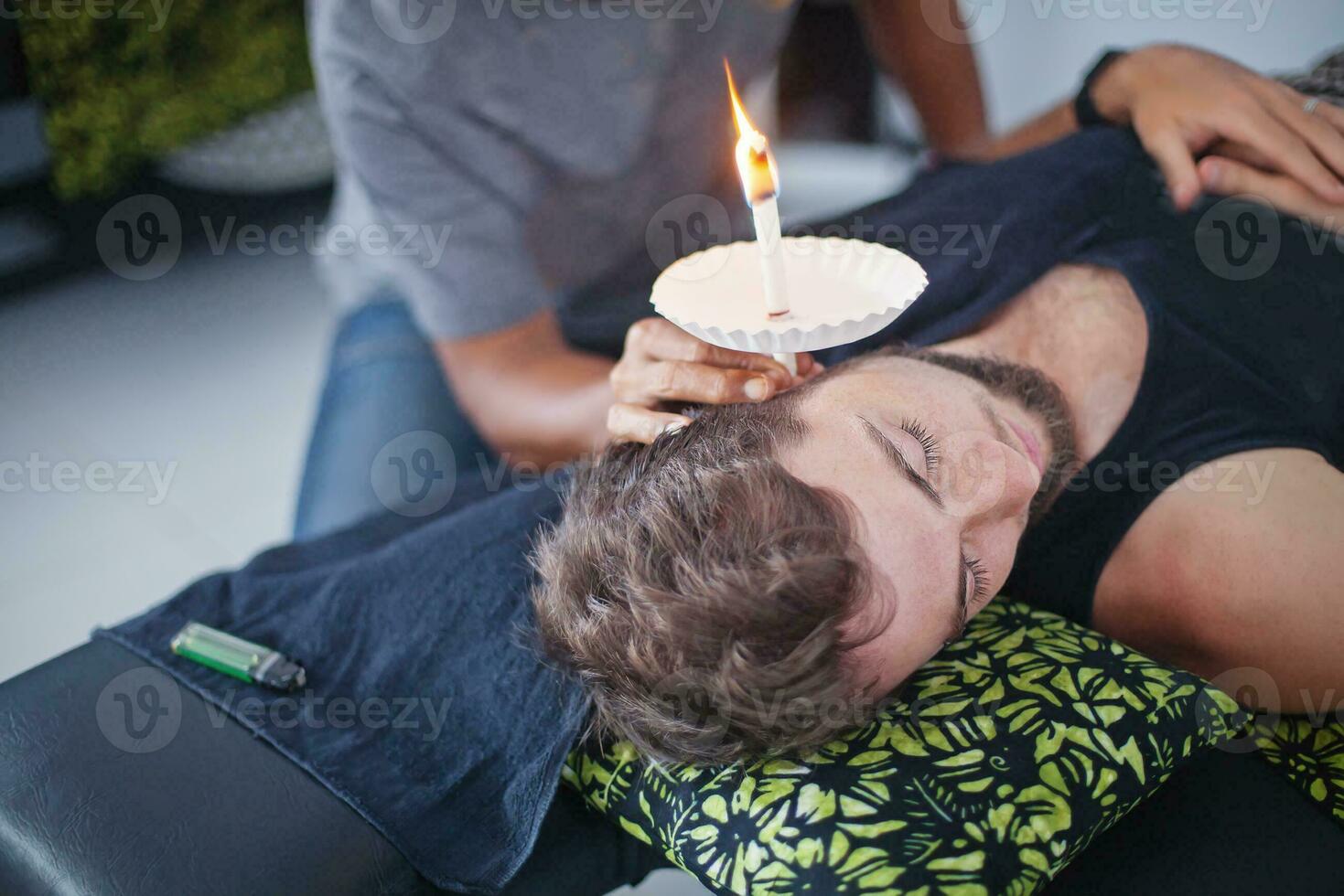 man having an ear candle therapy photo