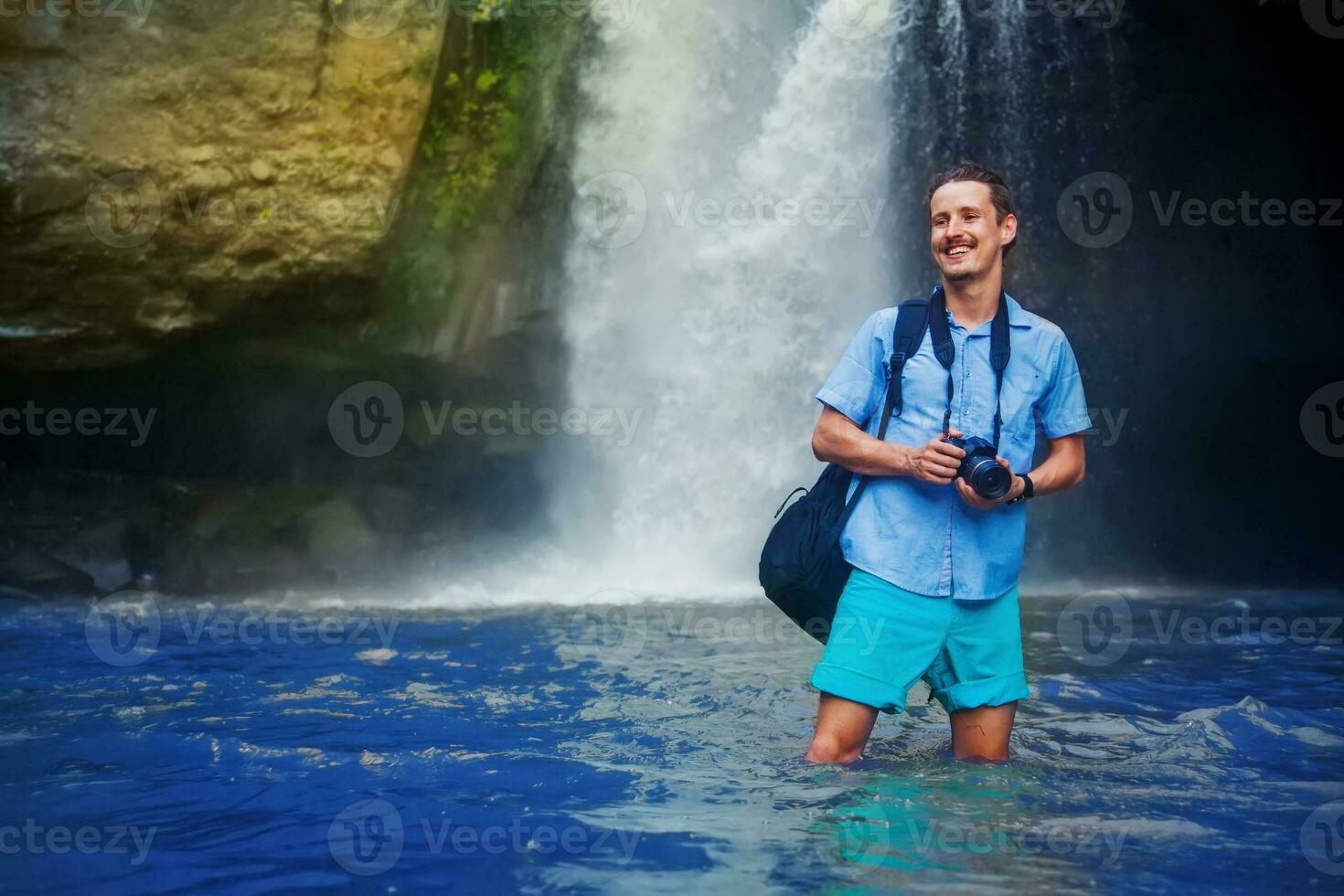 hombre teniendo un aventurero rastreo con cámara cerca el cascada en bali foto