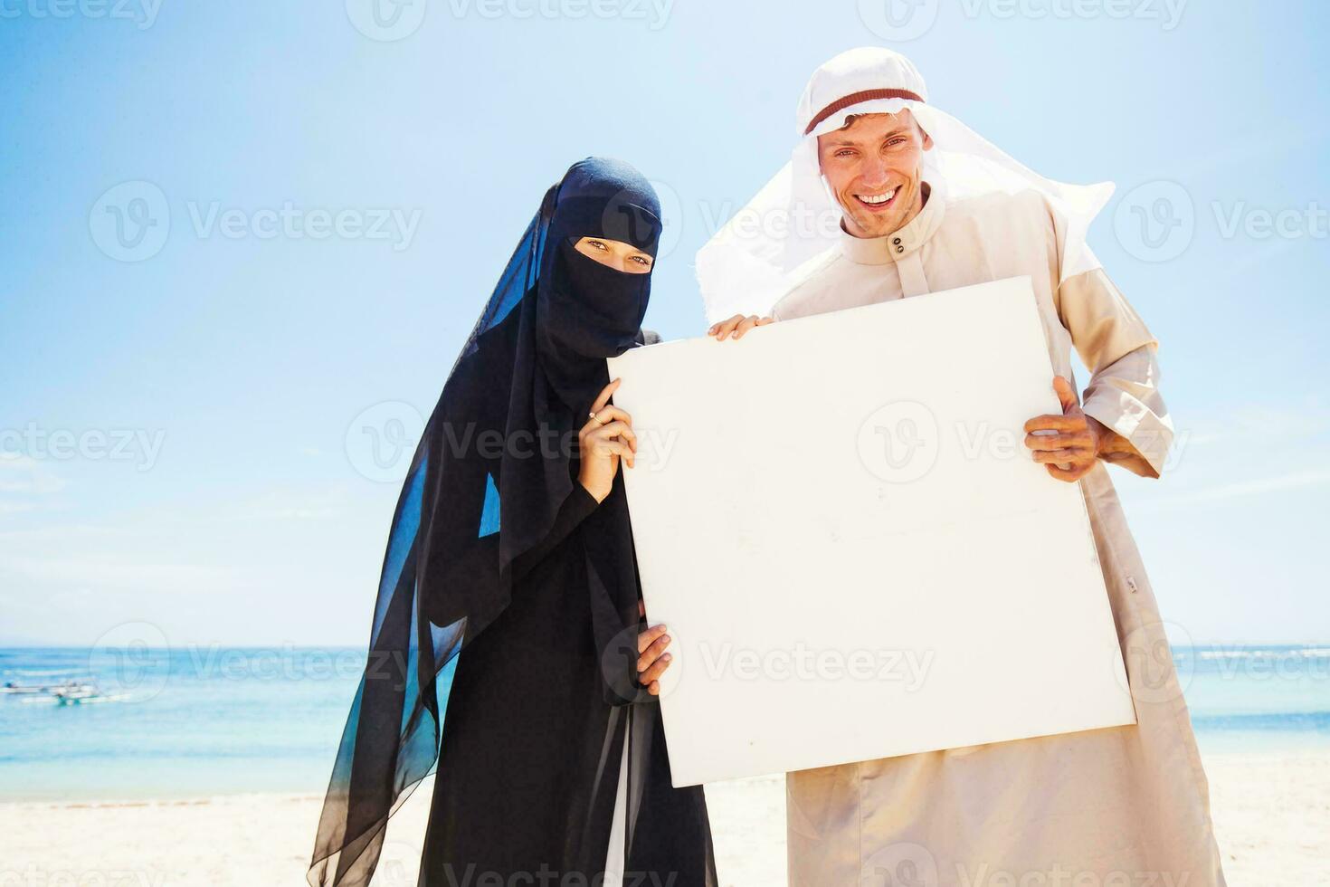 muslim couple on a beach wearing traditional dress photo