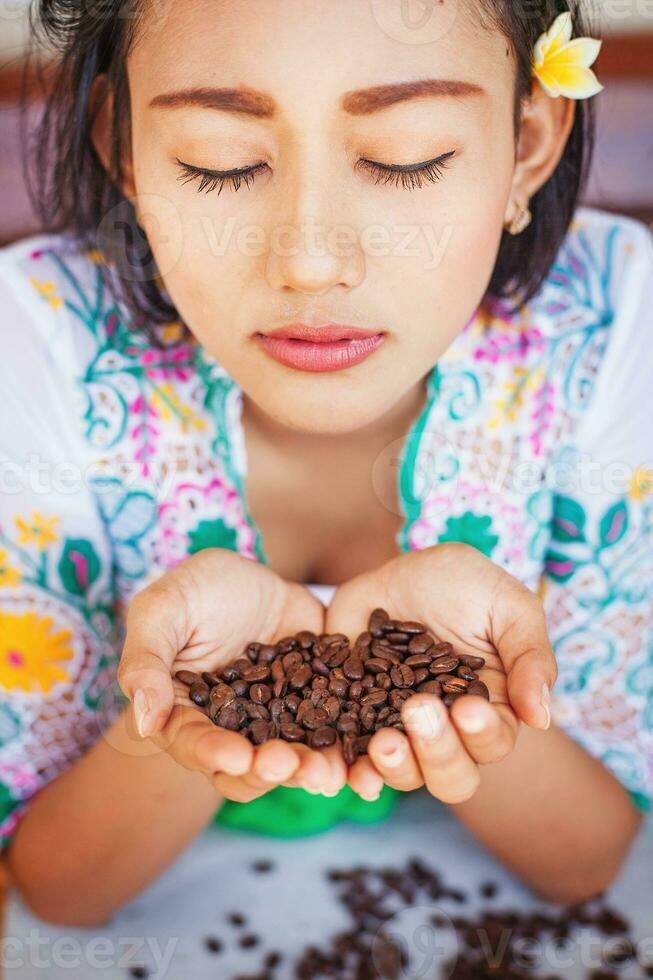 Balinese woman in traditional costume smelling coffee beans photo