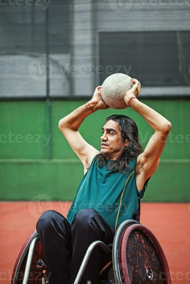 handsome determined disabled rugby player in a wheelchair practicing on a stadium photo