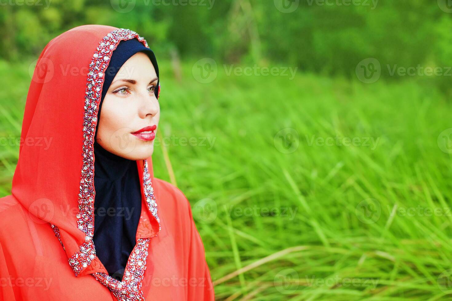 hermosa musulmán caucásico mujer vistiendo rojo vestir y hijab en el parque foto