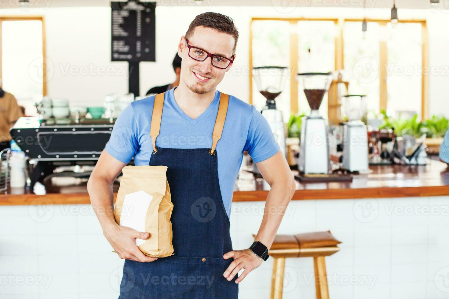 small cafe owner holding a package of coffee beans in front of the bar photo