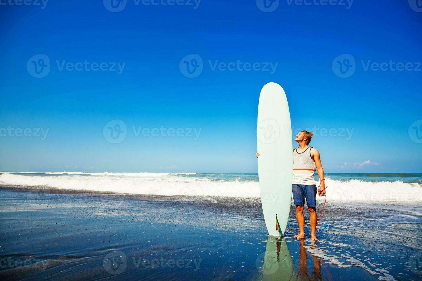 hombre con tabla de surf en pie en el apuntalar foto
