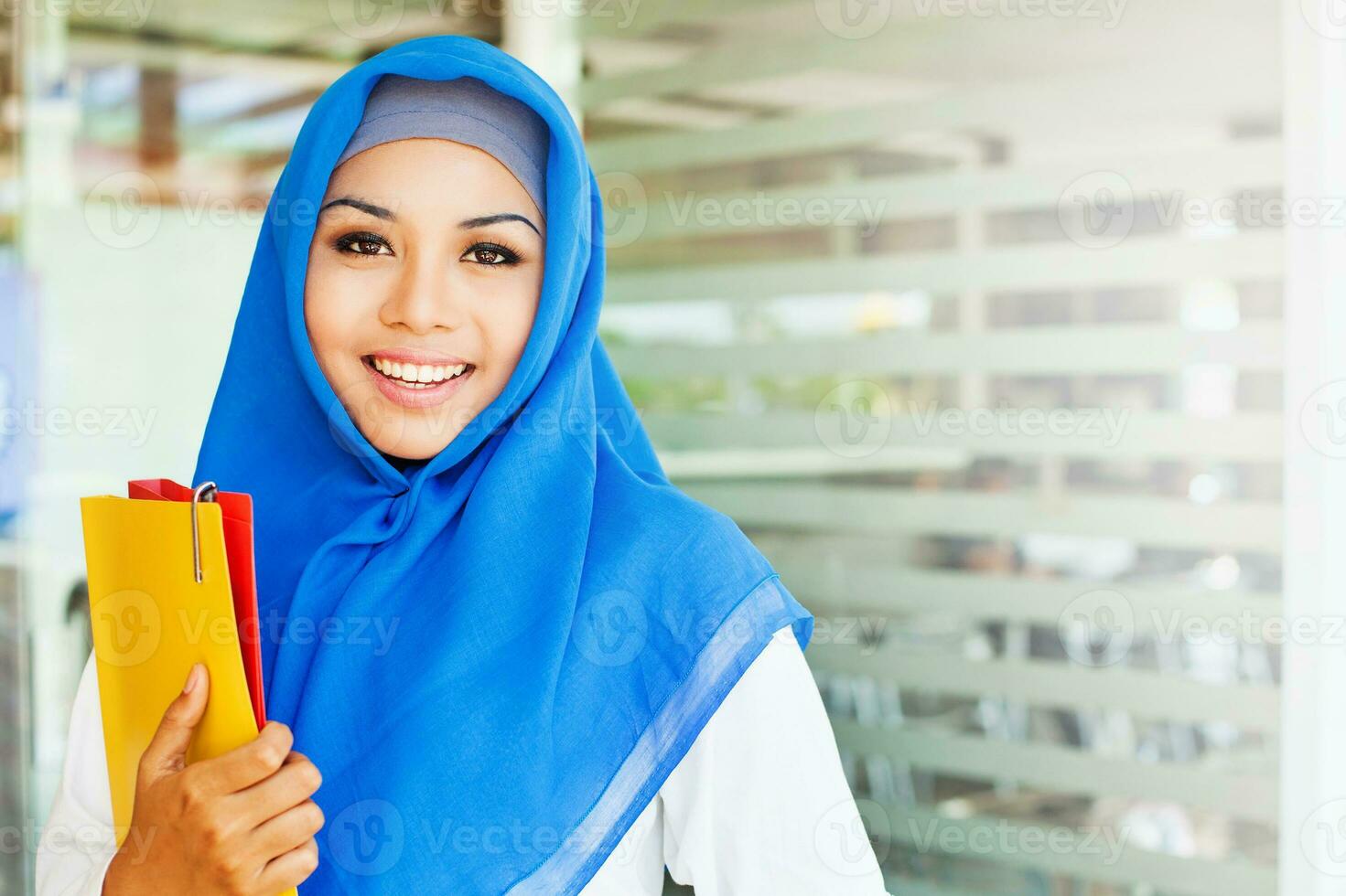 musulmán asiático chica, un Universidad alumno, participación su libros de trabajo en un clase habitación foto