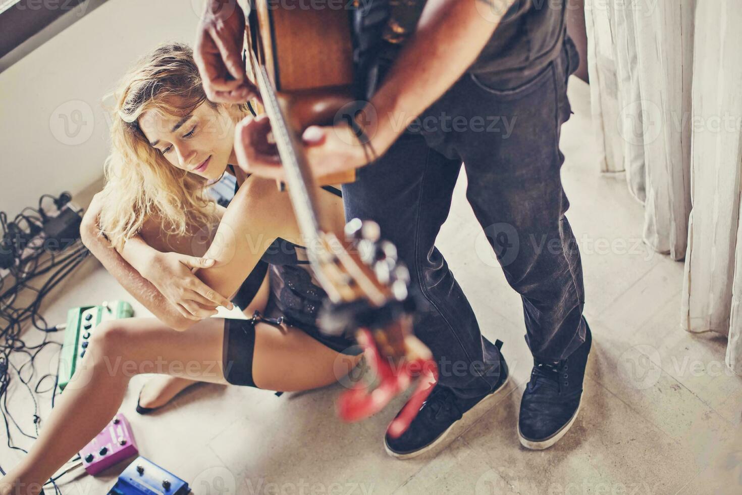 beautiful sexy girl watching her boyfriend playing guitar photo