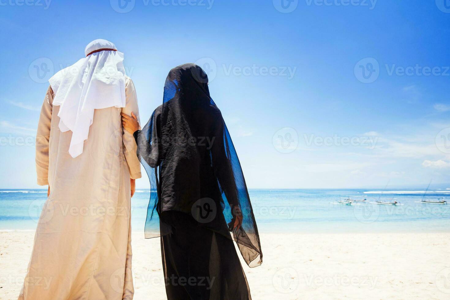 muslim couple on a beach wearing traditional dress photo